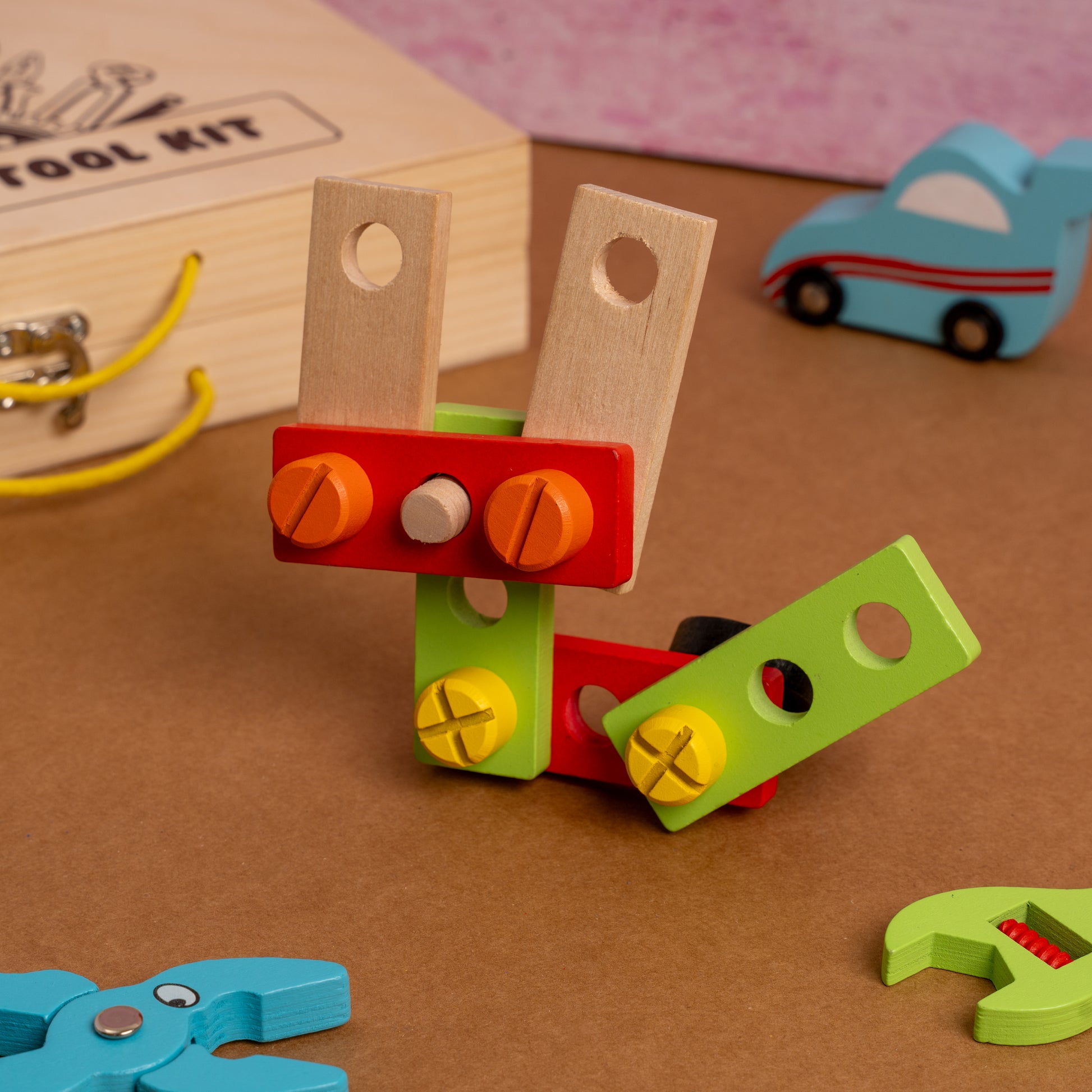NESTA TOYS – Wooden Construction Tool Kit Toy for Kids Colorful toy tool set with a wooden toolbox and car toy in the background