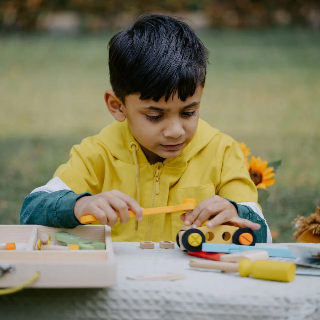 Boy assembling wooden tools from the Wooden Tool Kit Toy, practicing problem-solving and fine motor skills