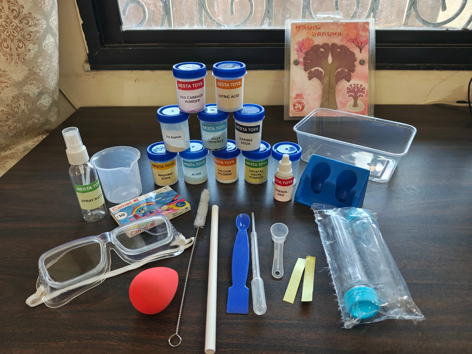 Kids chemistry lab kit with colorful experiment bottles, safety goggles, measuring tools, test tubes, and science accessories neatly arranged on a table for hands-on learning experiments.
